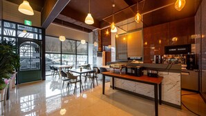 Interior moderno de café com balcão de mármore, área de estar e luminárias pendentes.