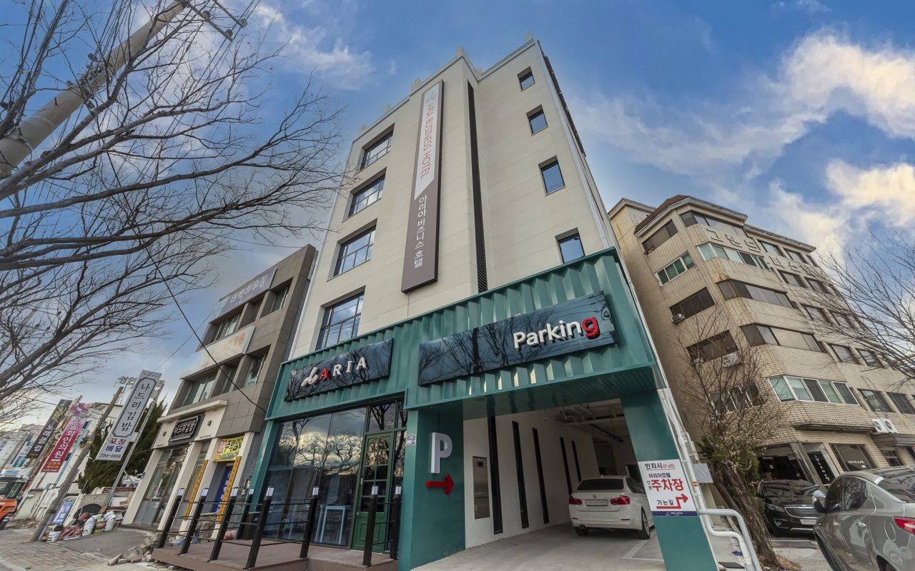 A multi-story building with a parking garage entrance, a sign for a parking facility, and various storefronts.