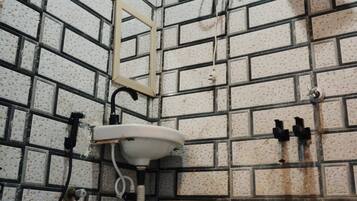 A bathroom with a white toilet, a green bucket, and a white sink.