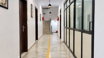A hallway with a yellow line on the floor, doors, framed pictures, and fire extinguishers.