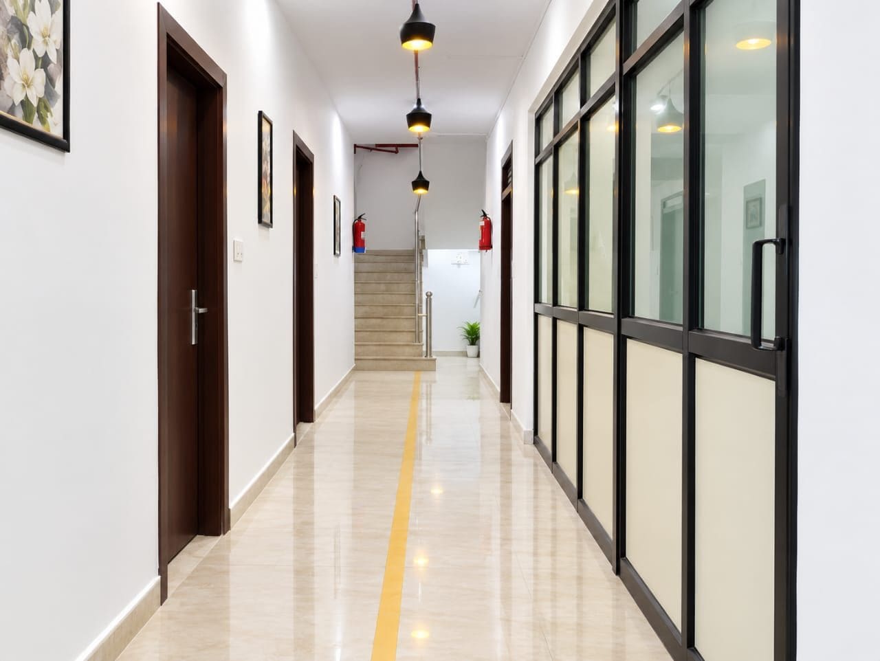 A corridor with a yellow tactile path, doors, and a staircase leading to an upper floor.