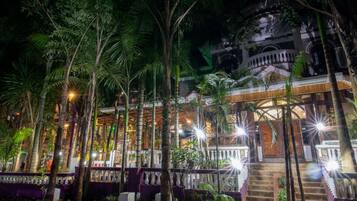 Un edificio con una escalera que lleva a un balcón, rodeado de palmeras e iluminado con luces.