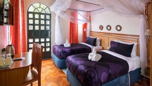 A hotel room with two beds, a dining table, and a window with curtains. - Palmera Gardens Hotel Murang'a (Murang'a)