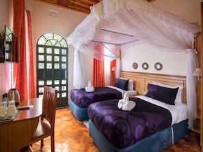 A hotel room with two beds, a dining table, and a window with curtains. - Palmera Gardens Hotel Murang'a (Murang'a)