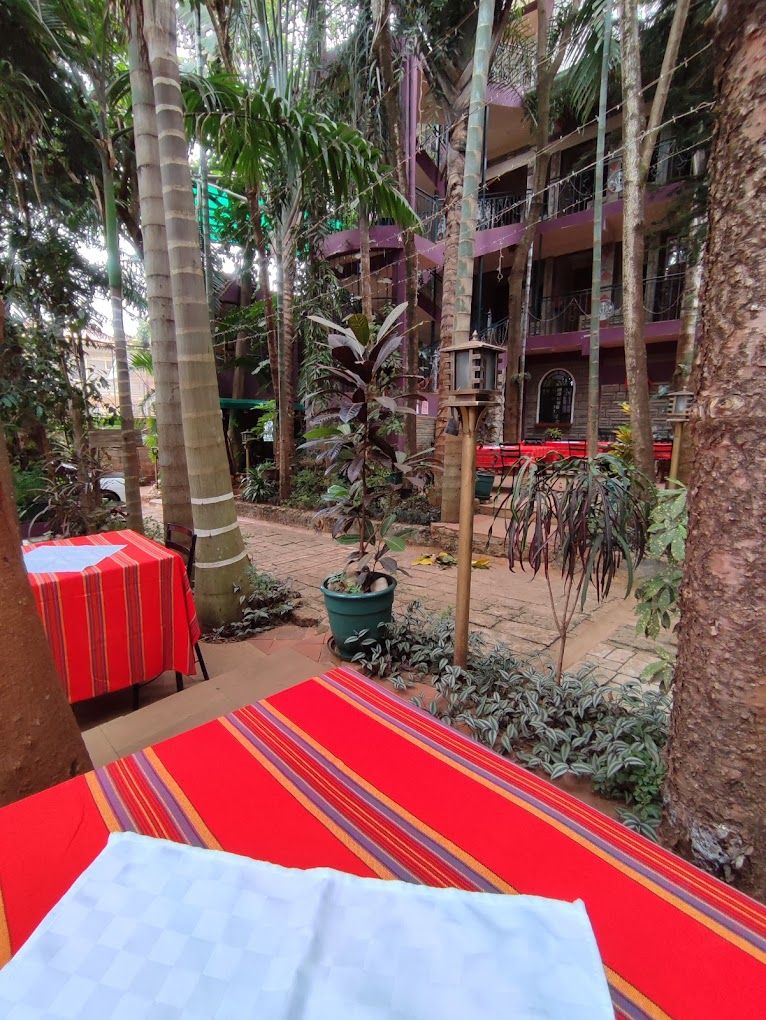 Un patio con una cama, una mesa con mantel rojo y una planta en maceta.