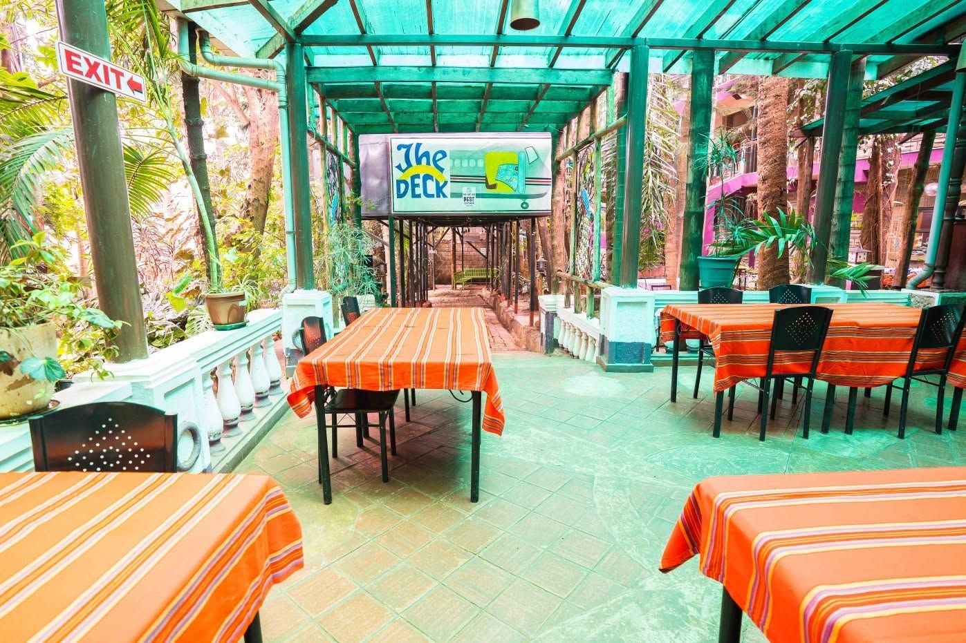 An outdoor dining area with tables and chairs, a sign for 'The Deck', and an exit sign.