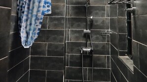 A modern shower with dark tiles, a visible shower head, and a towel rack. - Palmera Gardens Hotel Murang'a (Murang'a)