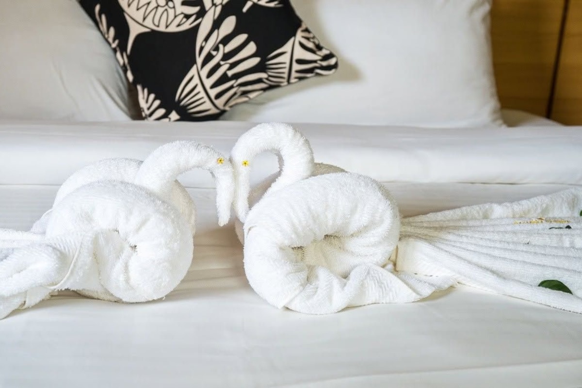 A bed with white bedding and a decorative pillow.
