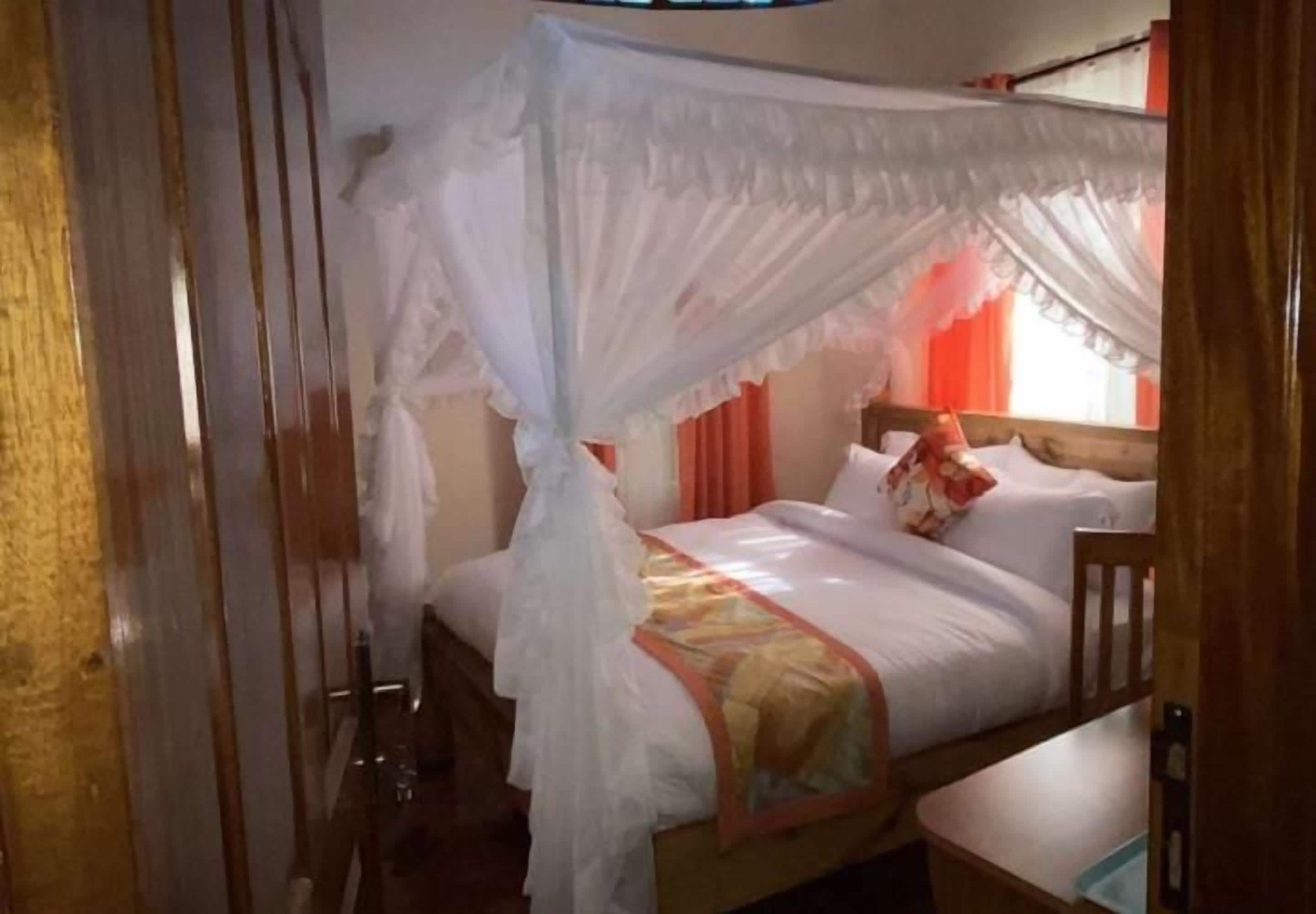 A single bed with a canopy, wooden headboard, and a bedside table.