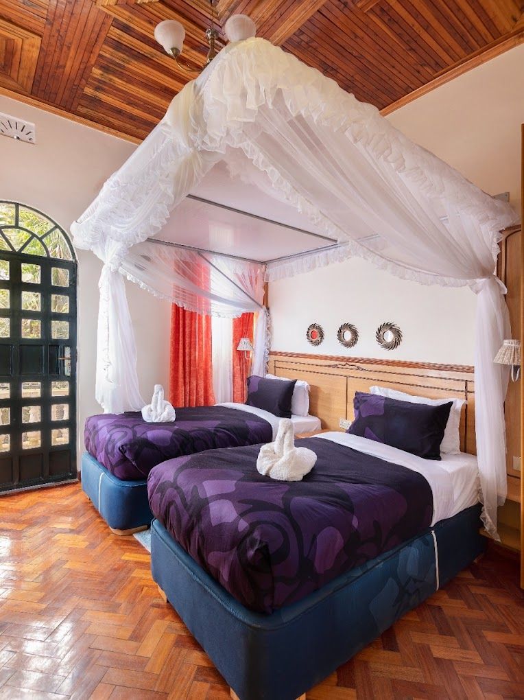 A room with a bed under a canopy, two bedside tables, and a wooden ceiling.