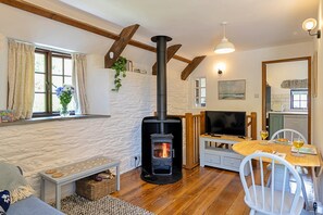Ein gemütliches Wohnzimmer mit Kaminofen, Fernseher und Essbereich mit Tisch und Stühlen.