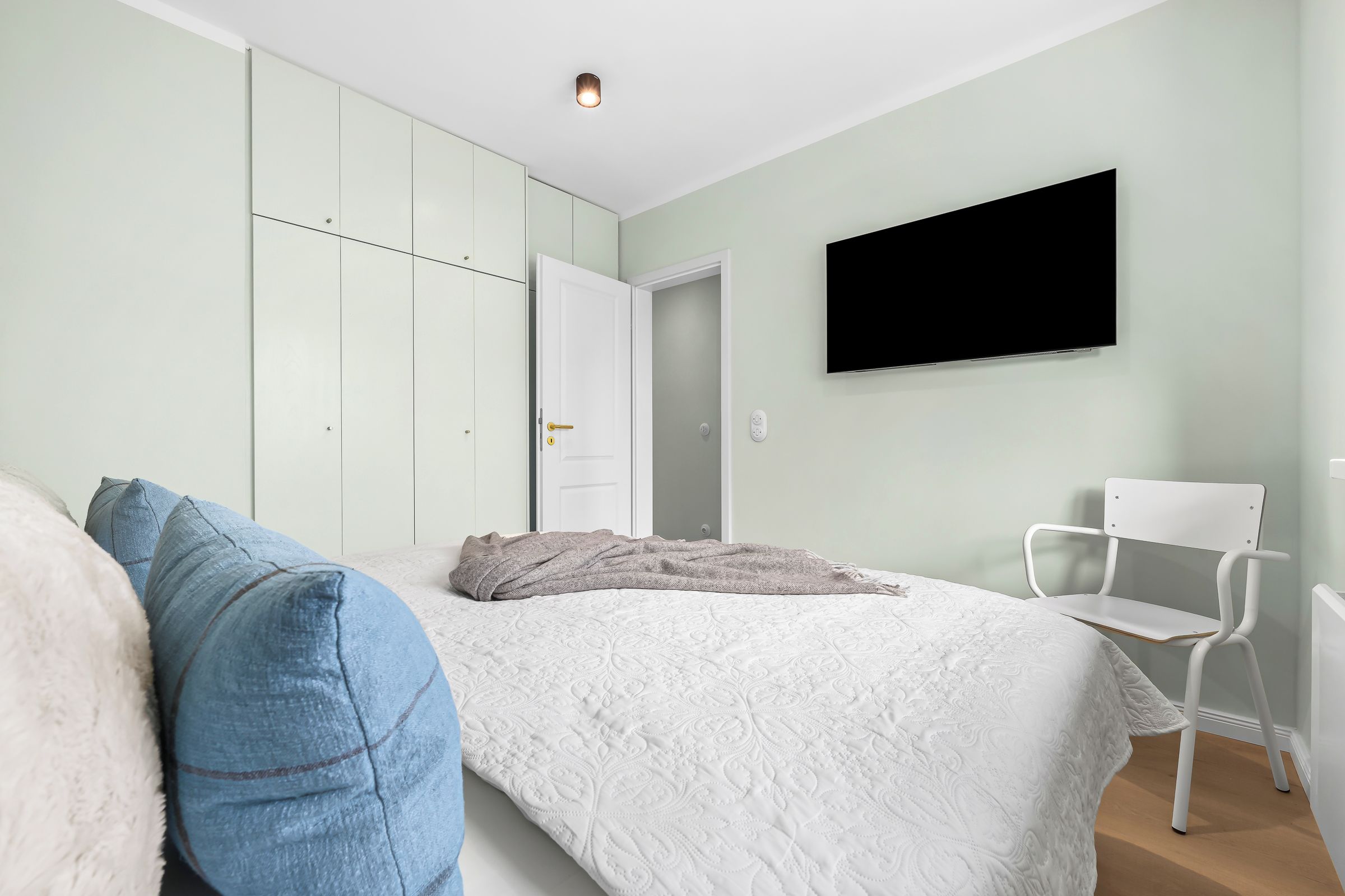 Ein Schlafzimmer mit einem Bett, einem Sessel, einem Fernseher und einem Kleiderschrank.