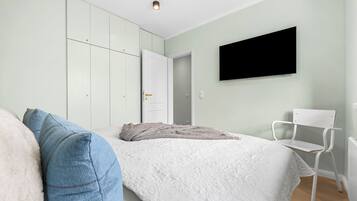 Ein Schlafzimmer mit einem Bett, einem Sessel, einem Fernseher und einem Kleiderschrank.