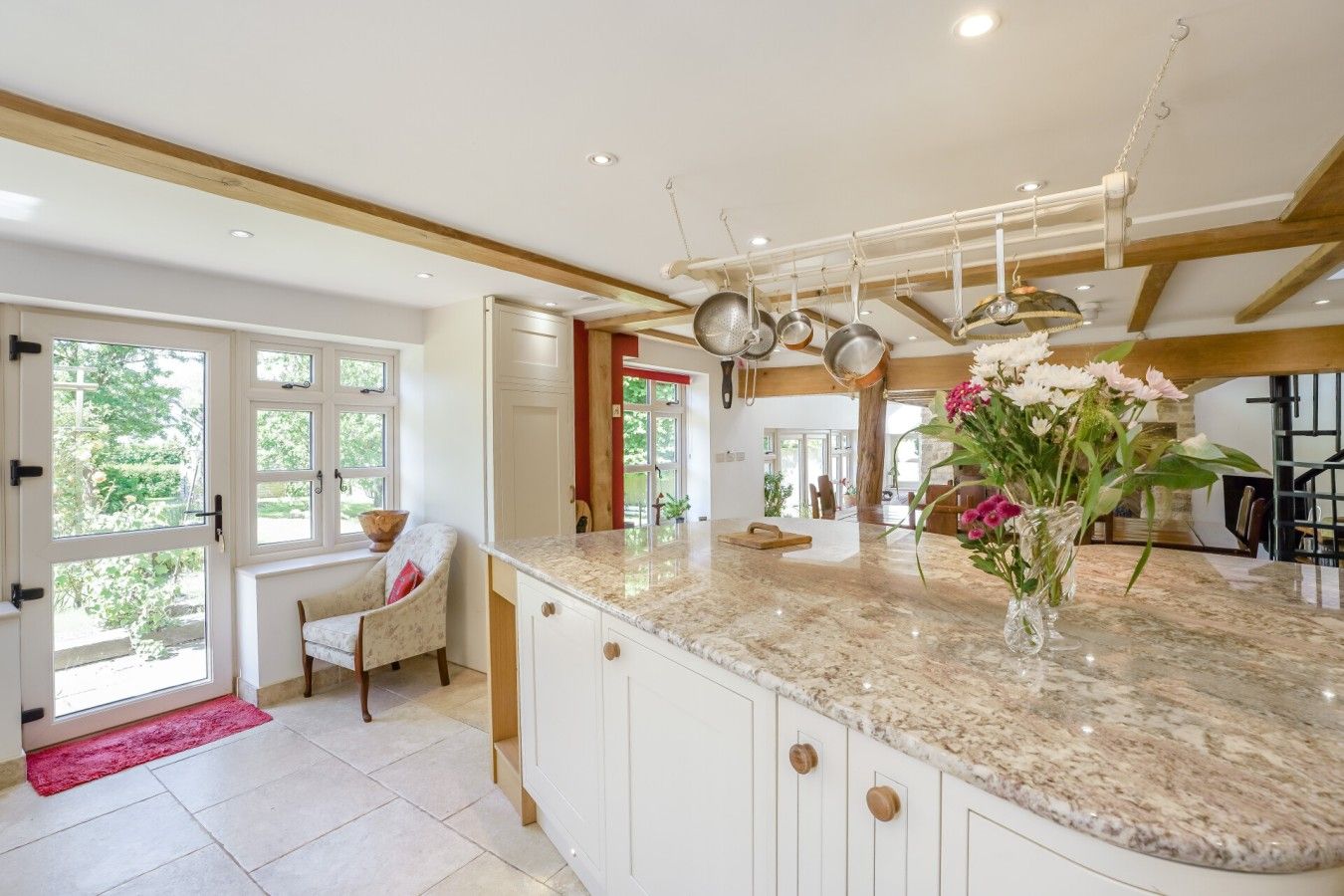 A spacious kitchen with a marble countertop, a dining area with a chair, and a large window.