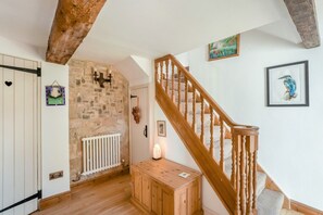 Eine Holztreppe mit einer Steinwand und einem Heizkörper.