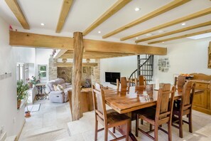 Ein geräumiger Essbereich mit Holztisch und -stühlen, einem Steinkamin und einer Treppe, die zu einer oberen Ebene führt.