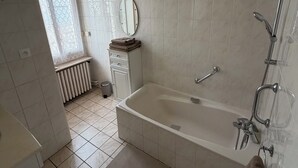 Un baño con bañera, espejo y radiador.