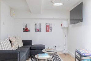 Una sala de estar moderna con un sofá, una mesa de centro y un televisor de pantalla plana montado en la pared.