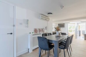 Un comedor moderno con una mesa larga, sillas y una pared blanca con obras de arte.
