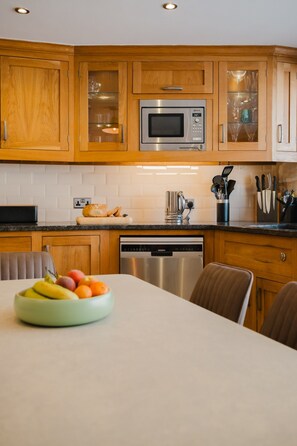 Une cuisine moderne avec des meubles en bois, un four à micro-ondes en acier inoxydable et un lave-vaisselle.