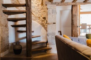 Un escalier en colimaçon avec des marches en bois et un mur en pierre rustique.