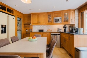 Une cuisine moderne avec des meubles en bois, un four à micro-ondes en acier inoxydable et un lave-vaisselle.