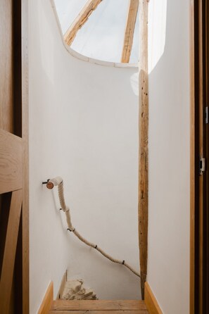 Un escalier étroit avec une rampe en bois et une échelle de corde.