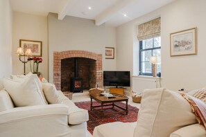 A living room with a brick fireplace, a television, and a comfortable seating area. - Elegant Escape at Dineter Wood House (Ewyas Harold)