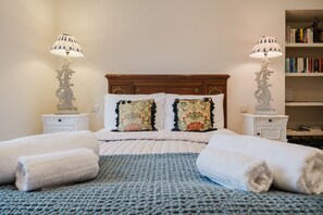 A neatly made bed with two pillows, a blue textured blanket, and two white bedside tables with lamps. - Elegant Escape at Dineter Wood House (Ewyas Harold)