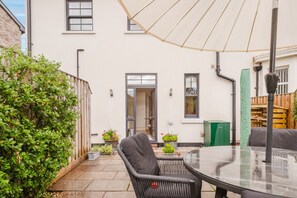 A patio with a glass table and chairs, surrounded by a white building with windows and doors. - Elegant Escape at Dineter Wood House (Ewyas Harold)