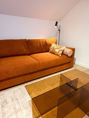 A modern living room with a sofa, a glass coffee table, and a floor lamp.