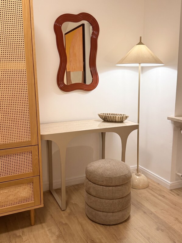 A room with a wooden cabinet, a desk, a lamp, and an ottoman.