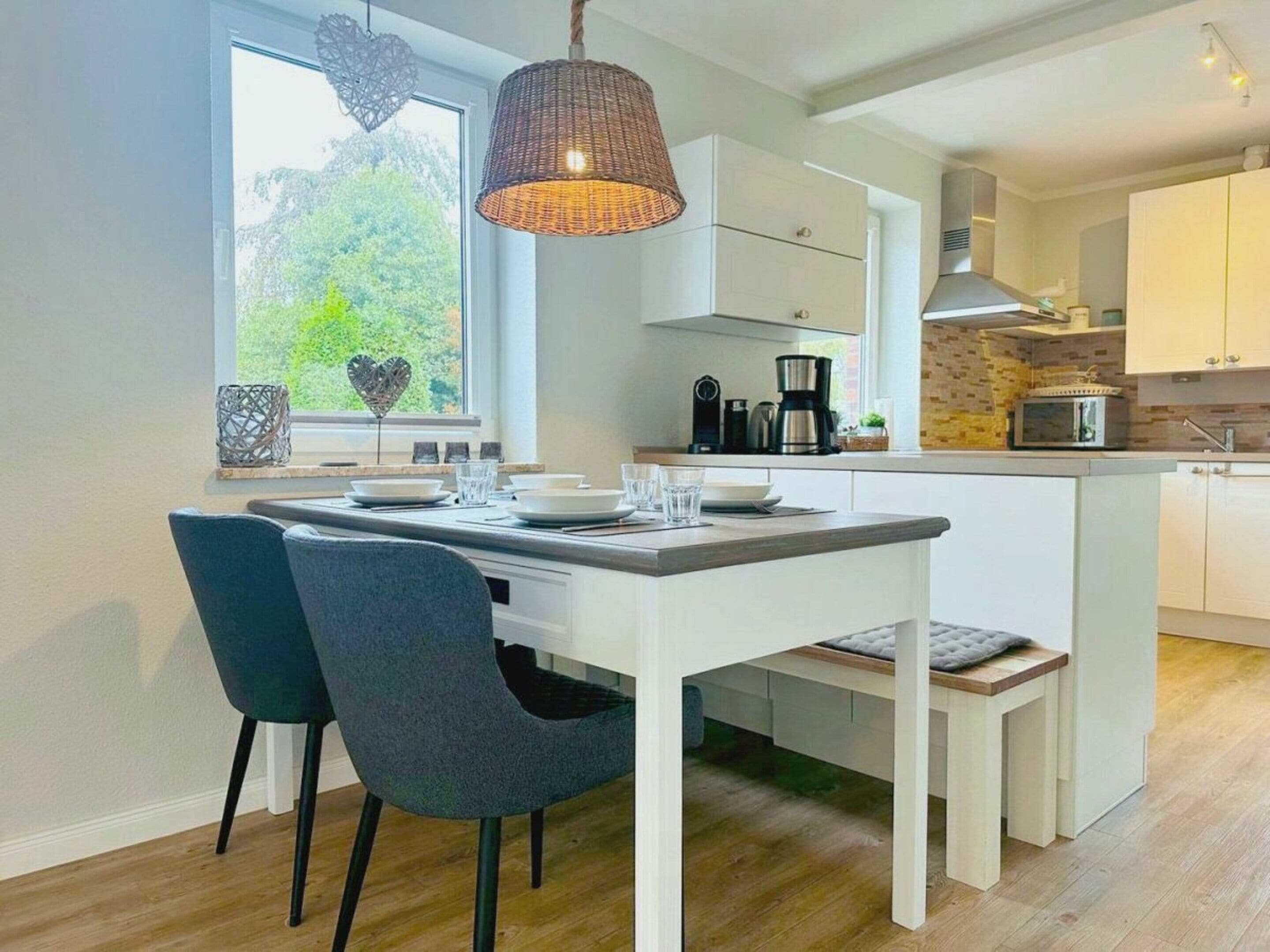 A modern kitchen with white cabinetry, a central island, and a hanging light fixture.