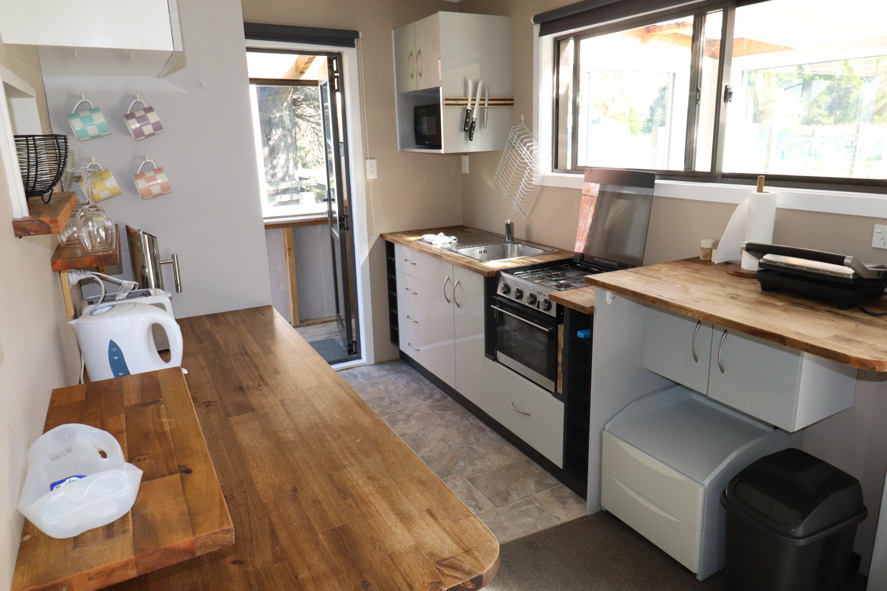 A compact kitchen with a wooden countertop, a stove, and a microwave.