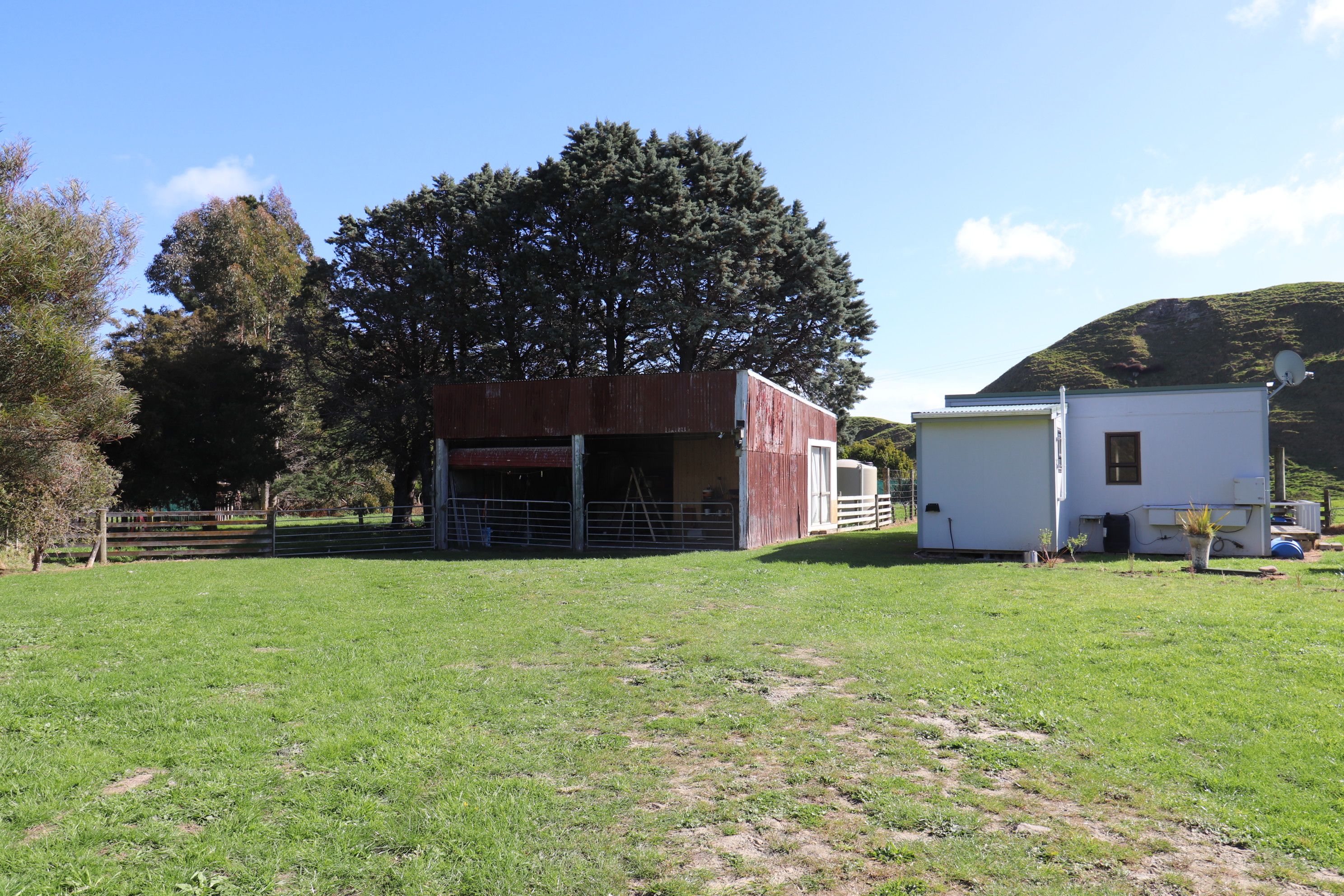 Une propriété rurale comprenant une grange, un petit bâtiment blanc et un grand arbre.