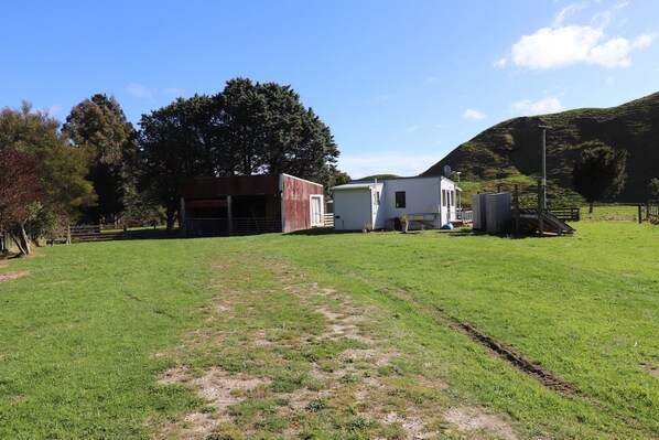 A rural property with a barn, a small white building, and a fenced pasture.