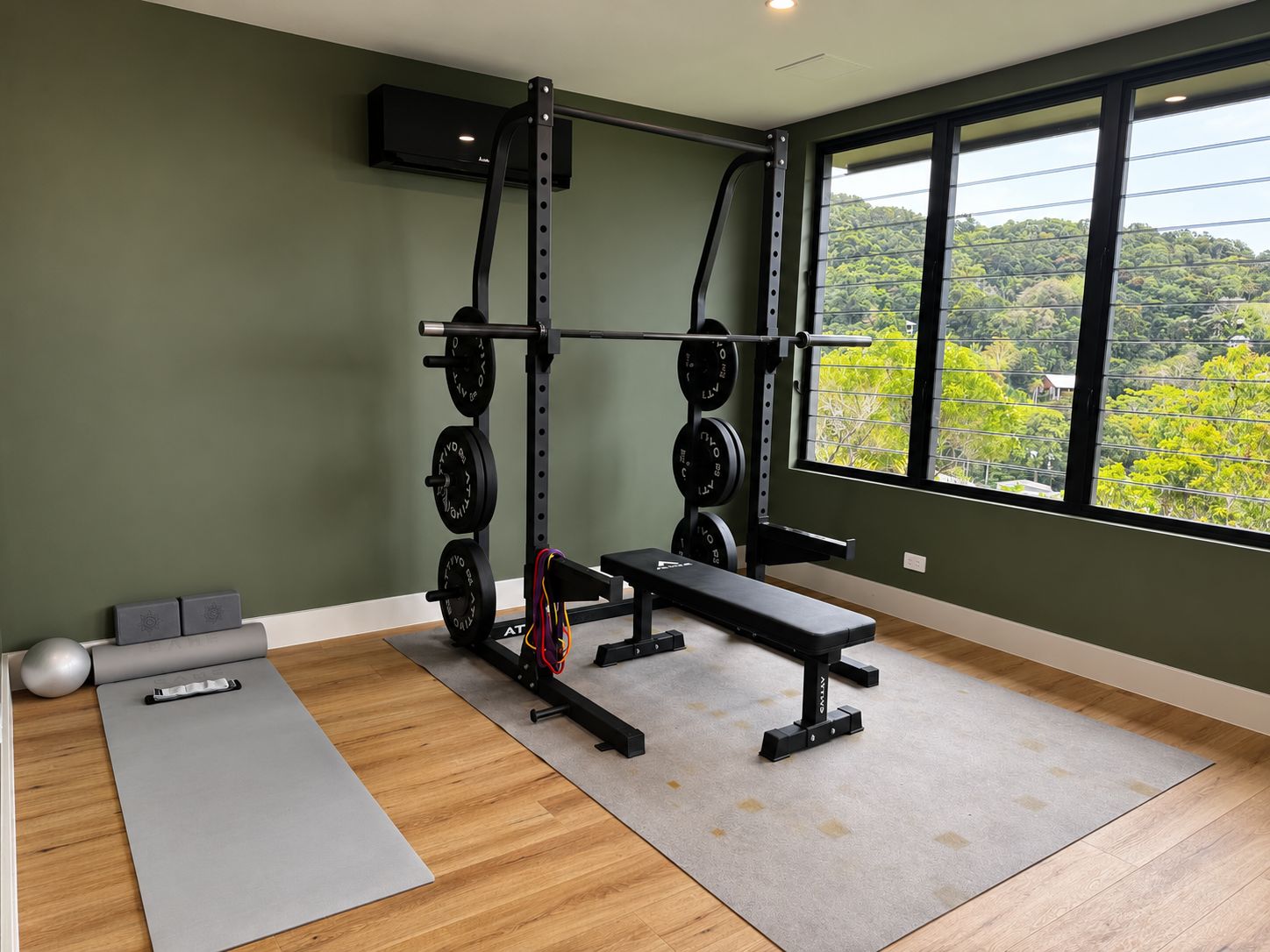A home gym with a squat rack, bench, and weight plates.