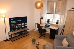 A modern living room with a TV, a desk, a laptop, a chair, a sofa, a coffee table, and a lamp. - Modern Scandinavian Apartment in Central Helsinki (Helsinki)