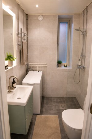 Een kleine badkamer met een wastafel, toilet en douche.