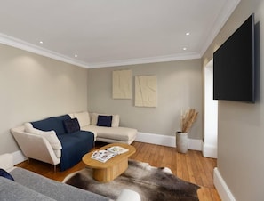 Una sala de estar moderna con un sofá, una mesa de centro y un televisor de pantalla plana montado en la pared.