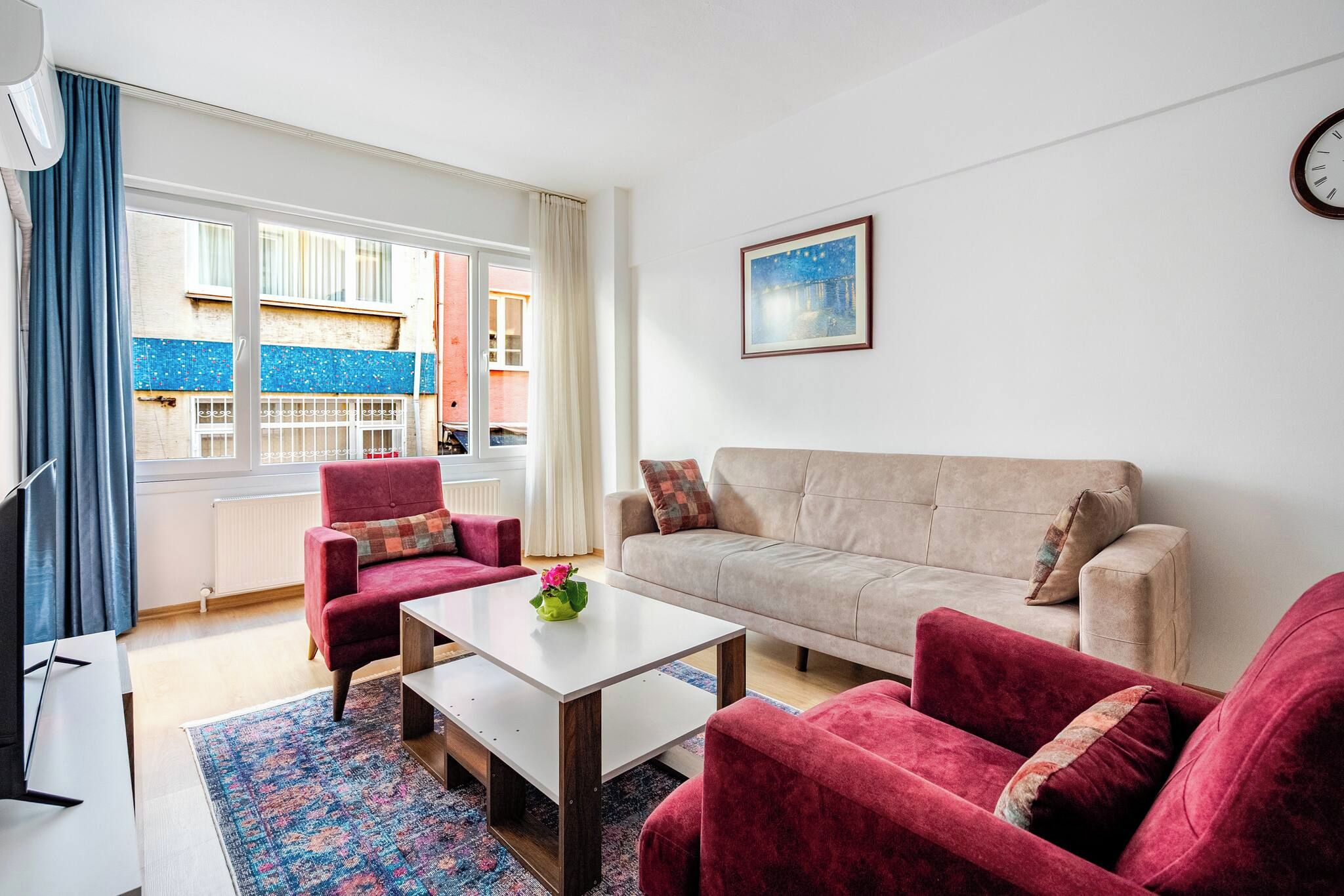 A living room with a sofa, two armchairs, a coffee table, and a painting on the wall.