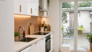 Een moderne keuken met witte kasten, een inbouwoven en een vaatwasser.