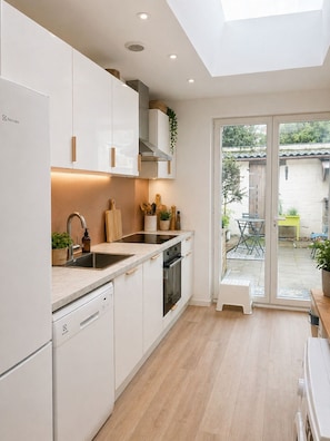 A modern kitchen with white cabinetry, a built-in oven, and a dishwasher. - Charming 4-bedroom house in Marcq-en-Barœul perfect for families & its Garden (Marcq-en-Barœul)