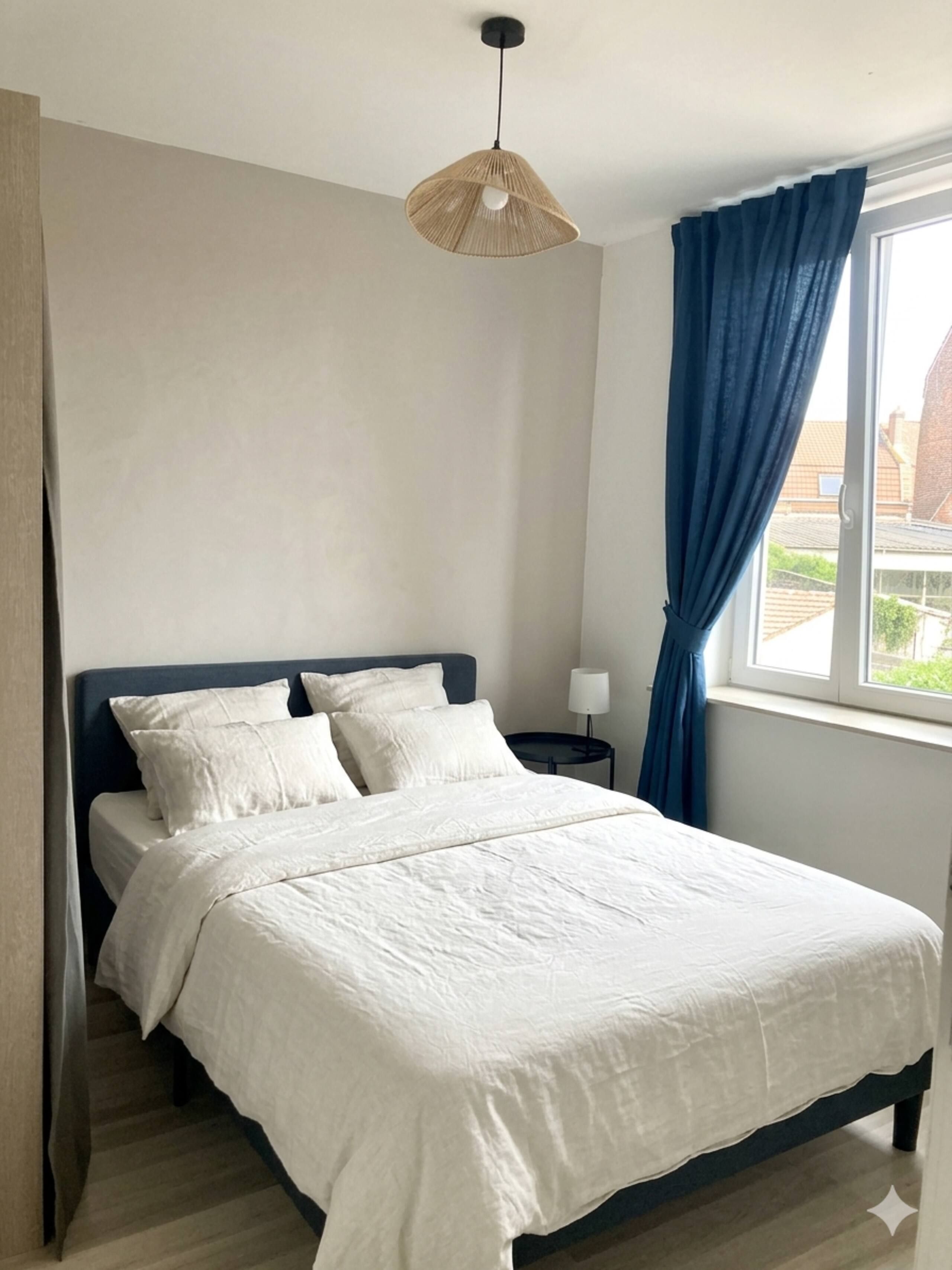 Een slaapkamer met een bed, een nachtkastje, een lamp, een raam met gordijnen en een hanglamp.