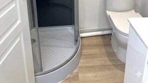 Een badkamer met een douchecabine van glas, toilet en een witte wastafel.