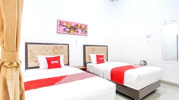 A hotel room with two beds, each with a headboard, a red and white bedspread, and a red pillow with 'OYO' branding.