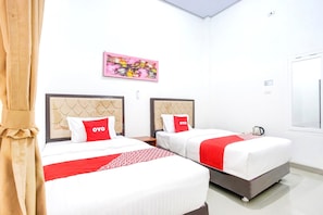A hotel room with two beds, each with a headboard, a red and white bedspread, and a red pillow with 'OYO' branding. - Luxury Twin Comfort Stay With Parking Access (Bandar Lampung)