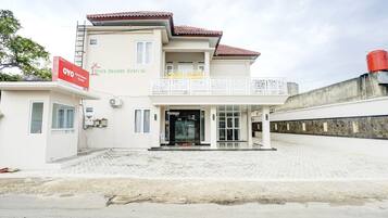 A two-story building with a balcony, a signboard, and a paved entrance area.