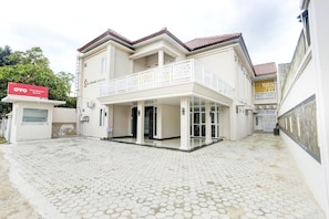 A two-story building with a balcony, a covered entrance, and a paved courtyard. - Luxury Twin Comfort Stay With Parking Access (Bandar Lampung)