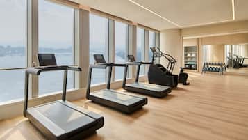 A gym with treadmills, a water bottle, and a view of a bridge.